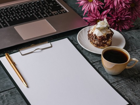 Bouquet of flowers, notebook, dessert and pen on wooden table.の写真素材
