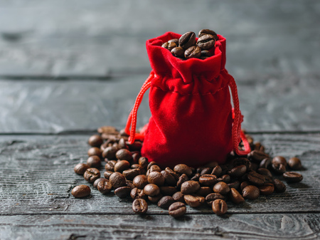 Red bag of roasted coffee beans on a dark wooden table. Grain for the preparation of aromatic beverage.の写真素材