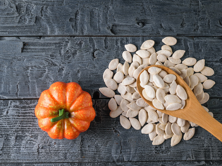 A bunch of pumpkin seeds and small pumpkin fruits on a dark rustic table. The view from the top.の写真素材