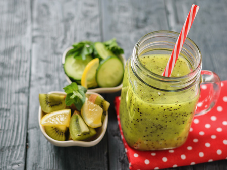 Mug with freshly made kiwi smoothie on a red rag on a rustic table. Healthy and nutritious vegetarian drink of fresh fruits and vegetables.の写真素材