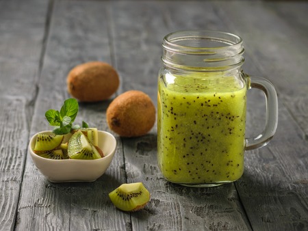 Freshly prepared smoothie of kiwi, Apple, mint and kiwi slices on the black rustic table.の写真素材
