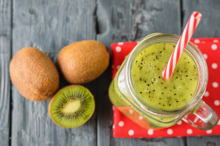 A mug with a kiwi smoothie and a bowl with kiwi slices on a rustic wooden table. The view from the top.の写真素材