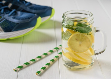 A freshly prepared drink made of lemon and mint on the background of sneakers wooden floor.の写真素材