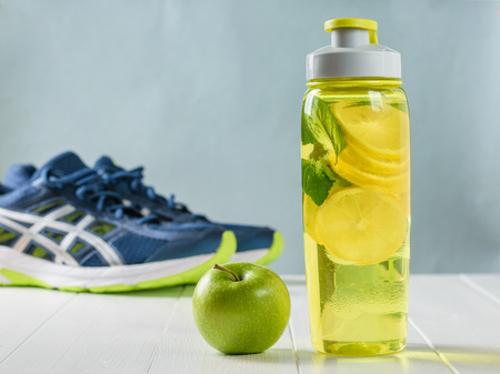 A freshly prepared drink made of lemon and mint on the background of sneakers wooden floor. Bottle for sports.の写真素材