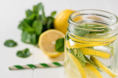Mug with a drink of lemon and mint on a white wooden table.の写真素材