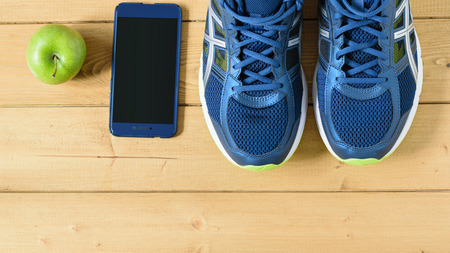 Running shoes, Apple and telephone on wooden floor. The view from the top. Flat lay.の写真素材