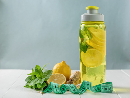 A freshly prepared drink made of lemon and mint and ginger on the background of sneakers wooden floor. Bottle for sports.の写真素材