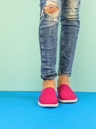 Hipster girl's legs in ripped jeans on the blue floor by the blue wall. Modern style. The concept of modern sports style.の写真素材