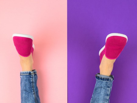Legs of the girl in red sneakers and ripped jeans on the purple and pink floor. The view from the top. The concept of modern sports style.の写真素材