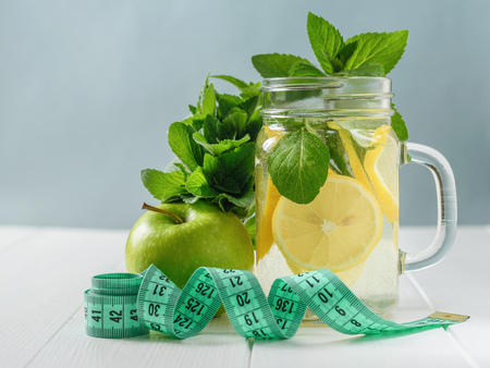 A freshly prepared drink made of lemon and mint and apple on a wooden white table. The concept of a healthy lifestyle.の写真素材