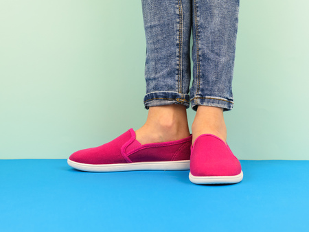 Hipster girl's legs in jeans on the blue floor by the blue wall. Modern style. The concept of modern sports style.の写真素材