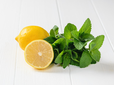 Lemon, and a bunch of mint on a white wooden table. The composition of the ingredients to make a...