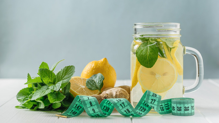 Measuring tape with a mug with a drink of lemon, mint and ginger on a white wooden table. The concept of a healthy lifestyle.の写真素材