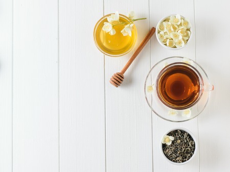 Freshly prepared tea with Jasmine flowers and honey on a white wooden table. The view from the top. Spring tea composition. Flat lay.の写真素材