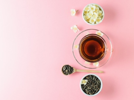 Herbal tea with Jasmine and a bowl of flowers on a pink table. The composition of the morning Breakfast. Spring tea composition on a white table. Flat lay.の写真素材