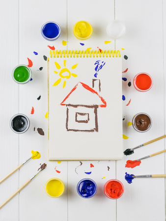 A drawing album with a brush and jars of paint on a white wooden table. Creative kit. Hobby and style. Flat lay.の写真素材