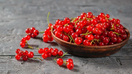 Freshly picked redcurrant berries in a clay bowl on a rustic table. The concept of healthy natural food.の写真素材