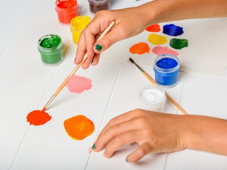 The girl picks up a pink color on a wooden table by mixing colors. Creative kit. Hobby and style.の写真素材