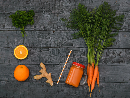 Freshly made carrot smoothie, bunch of carrots, orange and ginger root on a rustic table. The view from the top. The concept of healthy eating. Flat lay.の写真素材