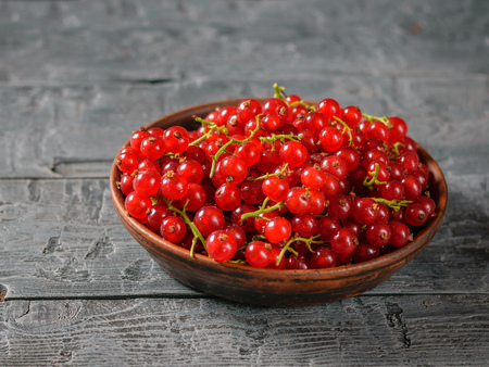 Freshly picked redcurrant berries in a clay bowl on a rustic table. The concept of healthy natural food.の写真素材