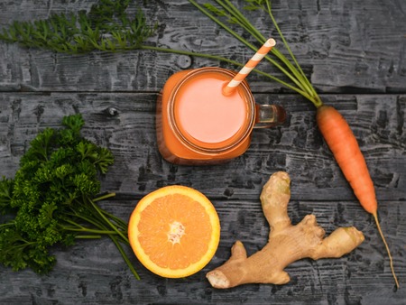 Freshly made carrot smoothie, carrot, orange and ginger root on a rustic table. The view from the top. The concept of healthy eating. Flat lay.の写真素材