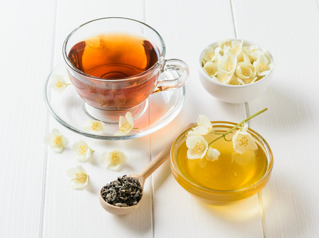Herbal tea, honey, Jasmine flowers and a wooden spoon on a white table. The composition of the morning Breakfast. Spring tea composition on a white table.の写真素材
