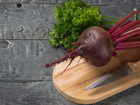 Fresh red beets with a knife and a bunch of parsley on the chopping Board. Health food. Vegetarian food.の写真素材