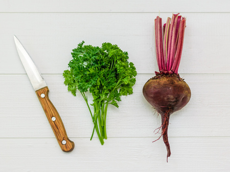 Fresh red beetroot with a knife and a bunch of parsley on a white wooden table. Health food. Vegetarian food. The view from the top. Flat lay.の写真素材