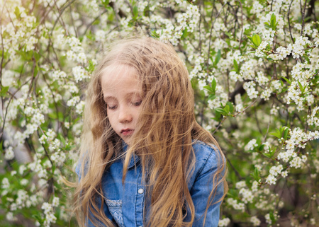 Hair in the wind close the girl's face in the cherry orchard. Portrait of laughing happy girl.の写真素材