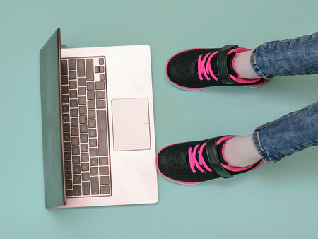 Girls legs in beautiful shoes in front of an open laptop at blue background. Modern education.の写真素材