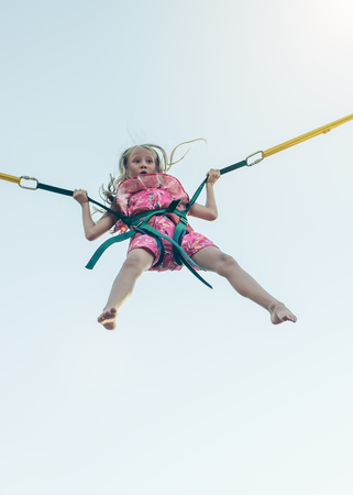 A girl in a dress flies up in stretch marks. A fascinating attraction in the amusement Park.の写真素材