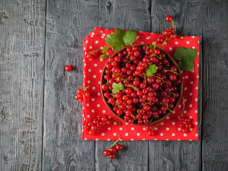 Clay bowl with red currant on pieces of beautiful fabric on rustic table. The concept of healthy natural food. Flat lay.の写真素材