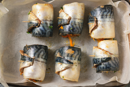 Six rolls of mackerel with vegetables stacked in a bowl for baking. A dish of sea fish stuffed with vegetables.の写真素材