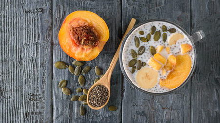 Chia seed pudding with peach and pumpkin seed on a dark wooden table. Diet food for weight loss and cleansing the body. The view from the top. Flat lay.の写真素材