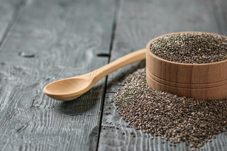 Wooden bowl with black Chia seeds and wooden spoon on rustic table. Vegetarian food. Diet for weight loss.の写真素材