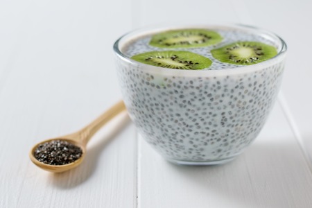 Glass bowl with milk Chia seed pudding on white wooden table. Diet food for weight loss and cleansing the body.の写真素材