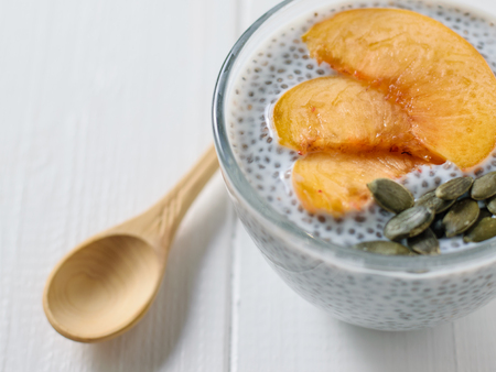 Peach slices with Chia pudding and pumpkin seeds on a white wooden table. Diet food for weight loss and cleansing the body.の写真素材