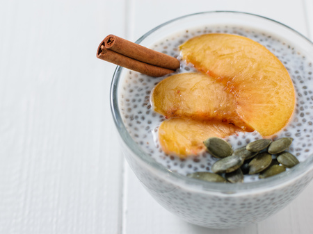 Chia seed pudding with slices peach on a white wooden table. Diet food for weight loss and cleansing the body.の写真素材