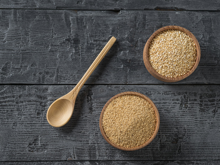 Two wooden bowls with amaranth and quinoa seeds on a dark wooden table. Gluten free food. The view from the top. Flat lay.の写真素材