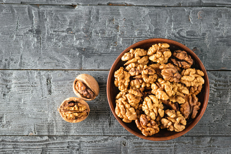 Split walnuts in a clay Cup on a wooden rustic black table. Natural and dietary food. The view from the top. Flat lay.の写真素材