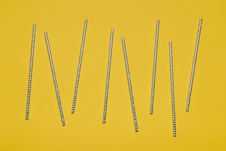 Striped cocktail straws on a yellow background. Minimalist style.の写真素材