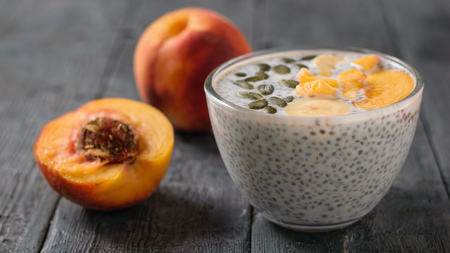 Ripe peach fruit and Chia seed pudding on a dark wooden table. Diet food for weight loss and cleansing the body.の写真素材