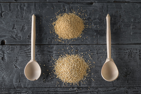 Two wooden spoons, a bunch of amaranth seeds and a bunch of quinoa seeds on a dark wooden table. Gluten free food. The view from the top. Flat lay.の写真素材