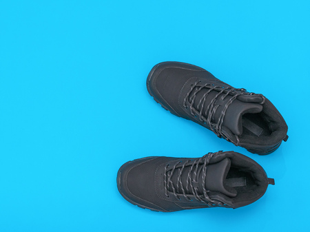 Insulated black casual men's shoes on blue and blue background. Men's shoes for cold weather. Casual sports men's shoes. Flat lay. The view from the top.の写真素材