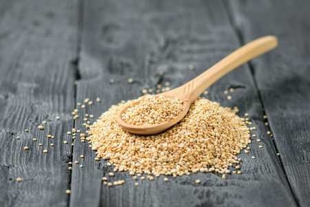 Wooden spoon in a pile of quinoa seeds on a dark wooden table. Gluten free food.の写真素材