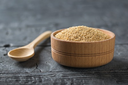 Wooden spoon and wooden bowl with amaranth seeds on black rustic table. Gluten free food.の写真素材