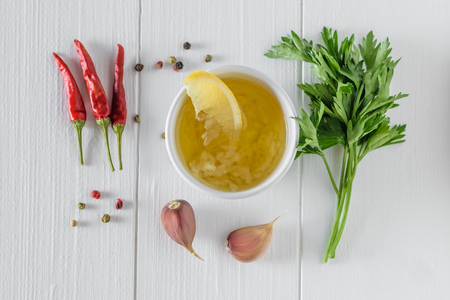Olive oil with garlic and lemon in a white bowl on a white table. Dressing for diet salad. Vegetarian food. The view from the top. Flat lay.の写真素材