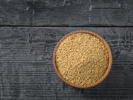 Wooden bowl with amaranth seeds on dark wooden table. Gluten free food. The view from the top. Flat lay.の写真素材