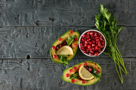 A bunch of parsley, a white bowl with pomegranate seeds and avocado on the village table. Vegetarian cuisine for weight loss. Healthy diet.の写真素材