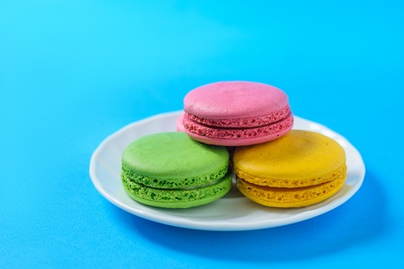 White Cup cakes with colorful macaroons on blue fanene. Freshly made homemade macaroons.の写真素材